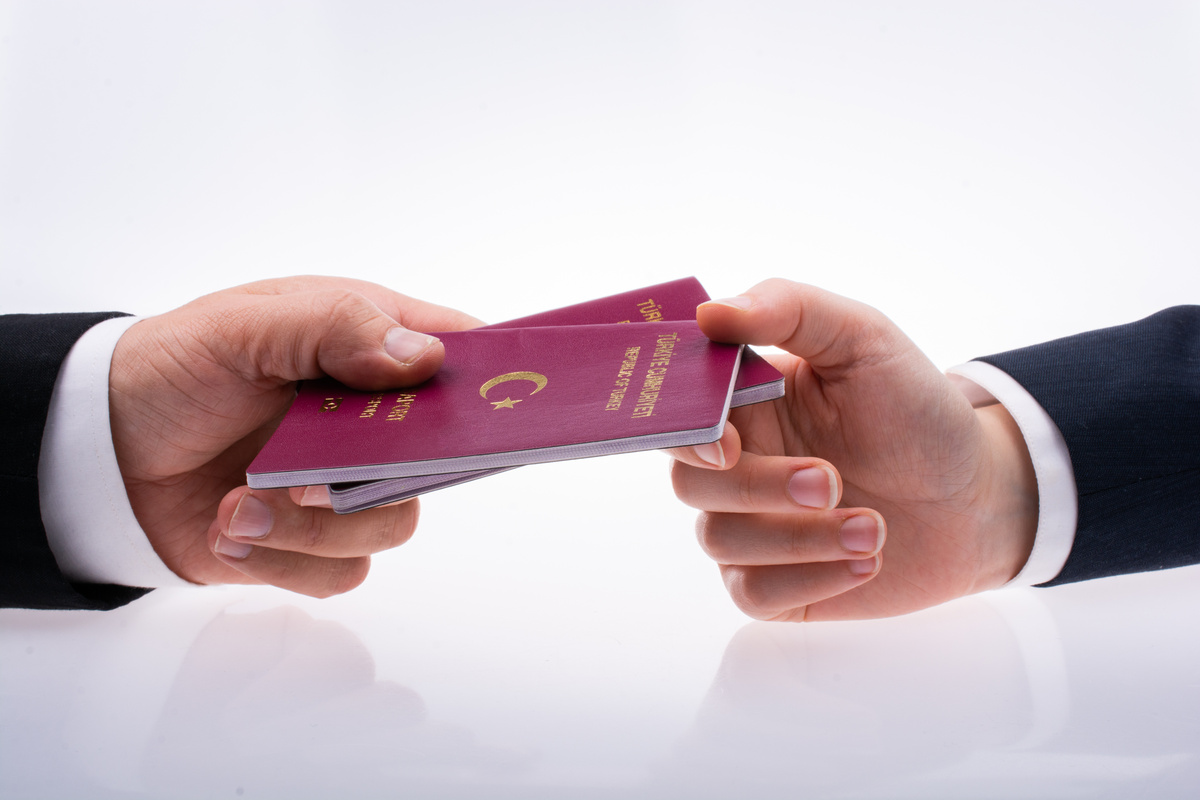 Hands Giving and Taking International Passport of a Citizen of T